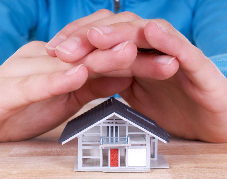 Schützende Hände über einem Haus